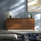 Credenza Modigliani Piombini a 3 ante in finitura Noce Naturale con decoro Comete; ambientazione in stile Contemporaneo Moderno con lampada Flos Taccia, vaso Venini Deco bianco e vaso Venini Ritaglio verde, tappeto contemporaneo blu e divano moderno grigio.